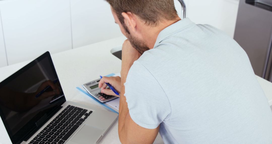 Man Calculating Finances on Calculator Near Laptop - Free Images, Stock Photos and Pictures on Pikwizard.com