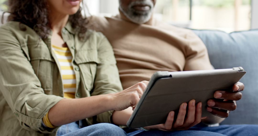 Couple Relaxing on Couch Using Tablet for Home Entertainment