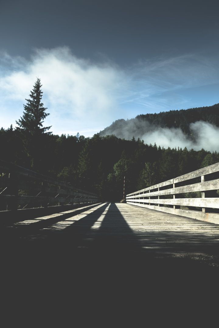 Tranquil Wooden Bridge in Forest with Mountain and Cloudy Sky Background - Free Images, Stock Photos and Pictures on Pikwizard.com