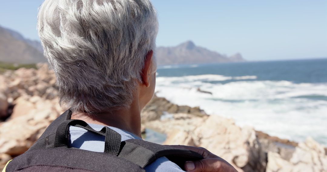 Senior Woman Enjoys Serene Coastal View with Backpack