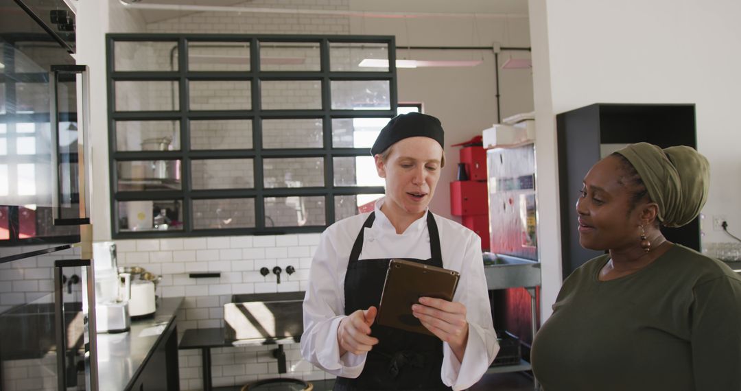 Chef Showing Menu to Restaurant Customer in Modern Kitchen - Free Images, Stock Photos and Pictures on Pikwizard.com