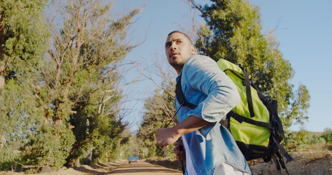 Young Man Hiking on Sunny Nature Trail with Backpack