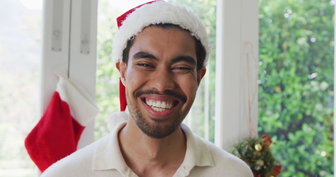 Smiling Man Wearing Santa Hat Celebrating Christmas Holiday - Free Images, Stock Photos and Pictures on Pikwizard.com