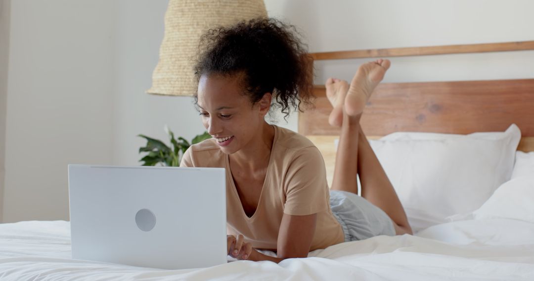 Woman Smiling on Bed with Laptop Enjoying Relaxed Home Office Mood