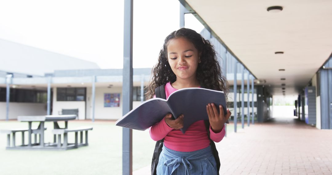 Young Girl Reading Book in School Corridor with Focused Expression