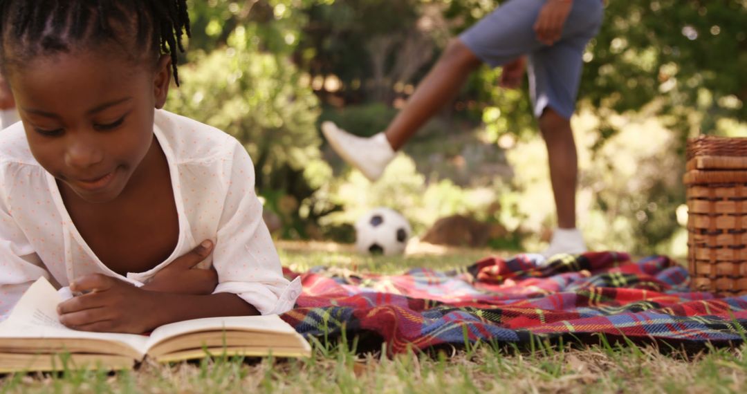 Young Girl Reading on Picnic Blanket with Soccer Background - Free Images, Stock Photos and Pictures on Pikwizard.com