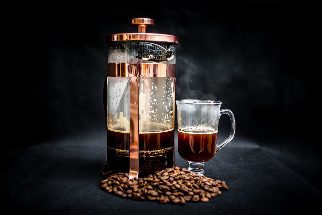 French Press Coffee alongside Glass Mug and Coffee Beans