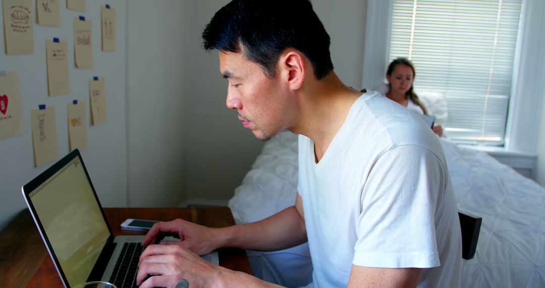 Man Working on Laptop at Home While Woman Uses Tablet - Free Images, Stock Photos and Pictures on Pikwizard.com