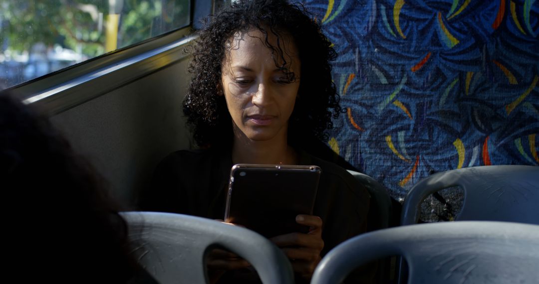 African american woman sitting in city bus using tablet - Free Images, Stock Photos and Pictures on Pikwizard.com