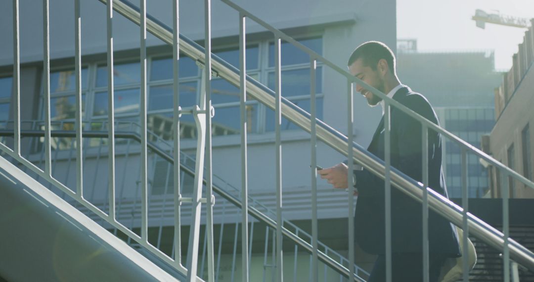 Businessman Walking Down Stairs Checking Smartphone in Urban Area - Free Images, Stock Photos and Pictures on Pikwizard.com