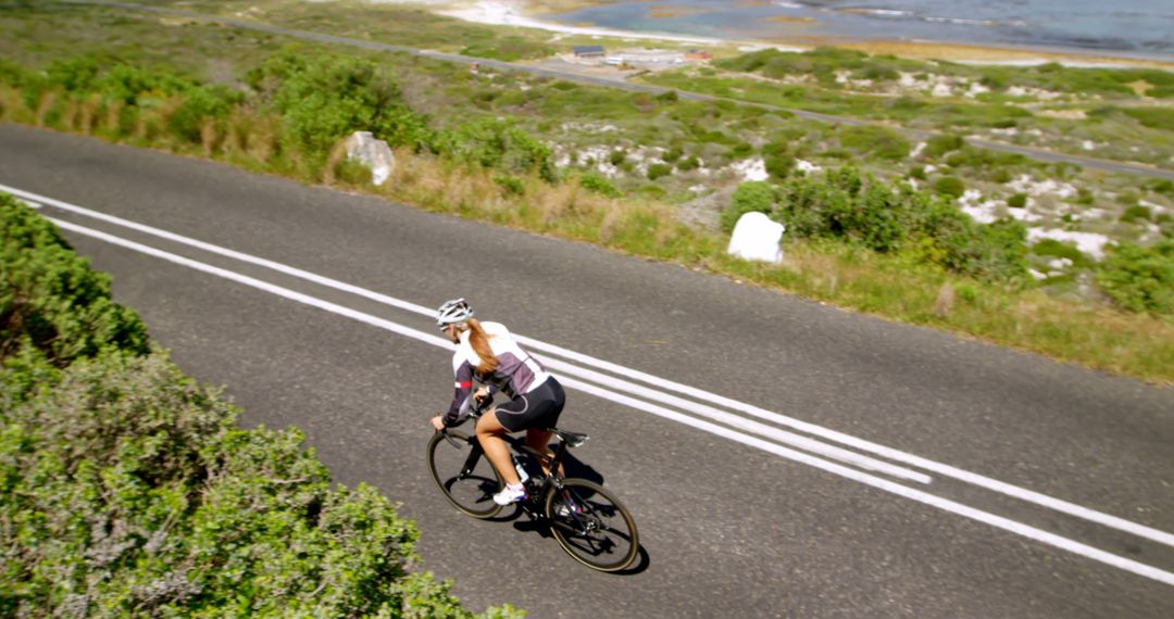 Woman Cycling on Scenic Coastal Road on Sunny Day - Free Images, Stock Photos and Pictures on Pikwizard.com