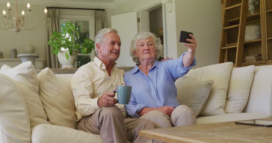 Smiling caucasian senior couple taking a selfie from smartphone sitting on the couch at home - Free Images, Stock Photos and Pictures on Pikwizard.com
