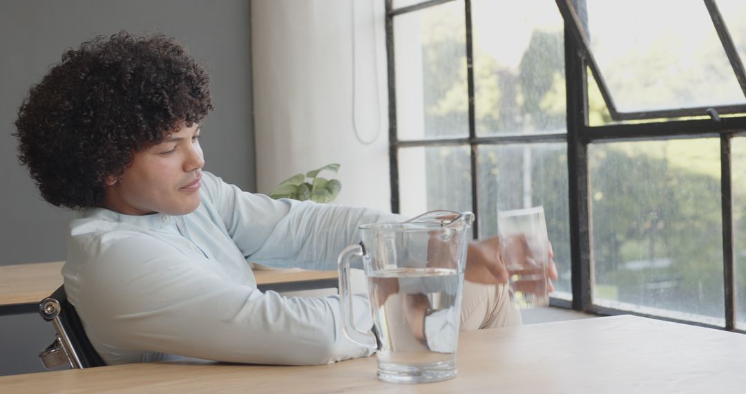 Young Professional Relaxing with Glass of Water by Office Window