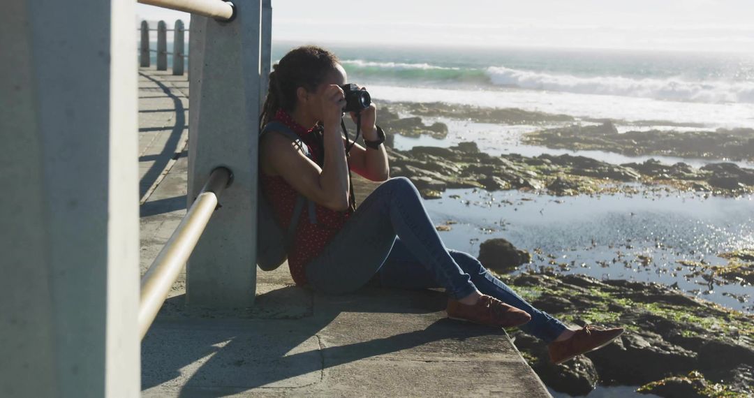 Woman photographing tidal pools from pier at coastline during low tide with DSLR camera