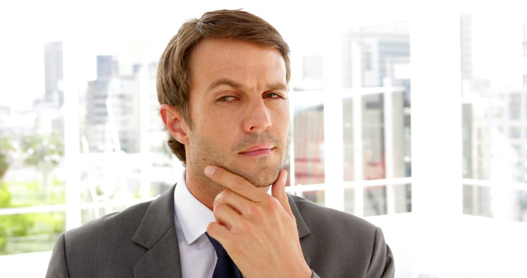 Businessman Contemplating with Hand on Chin in Office - Free Images, Stock Photos and Pictures on Pikwizard.com