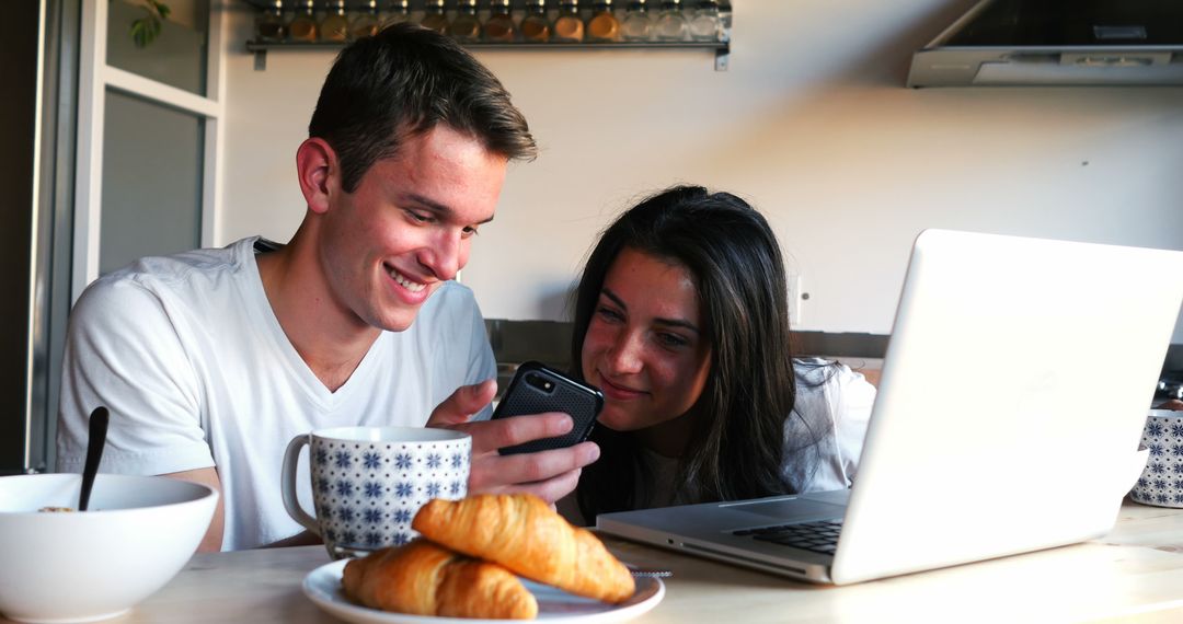 Happy Couple Enjoying Breakfast with Technology in Kitchen