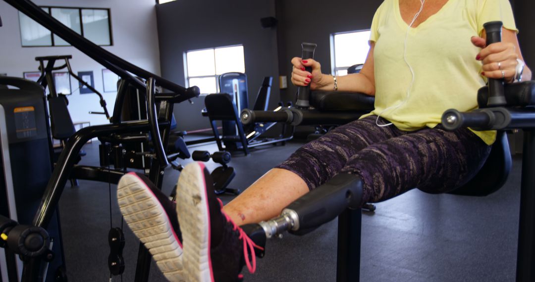 Woman Exercising on Gym Equipment Wearing Earphones - Free Images, Stock Photos and Pictures on Pikwizard.com