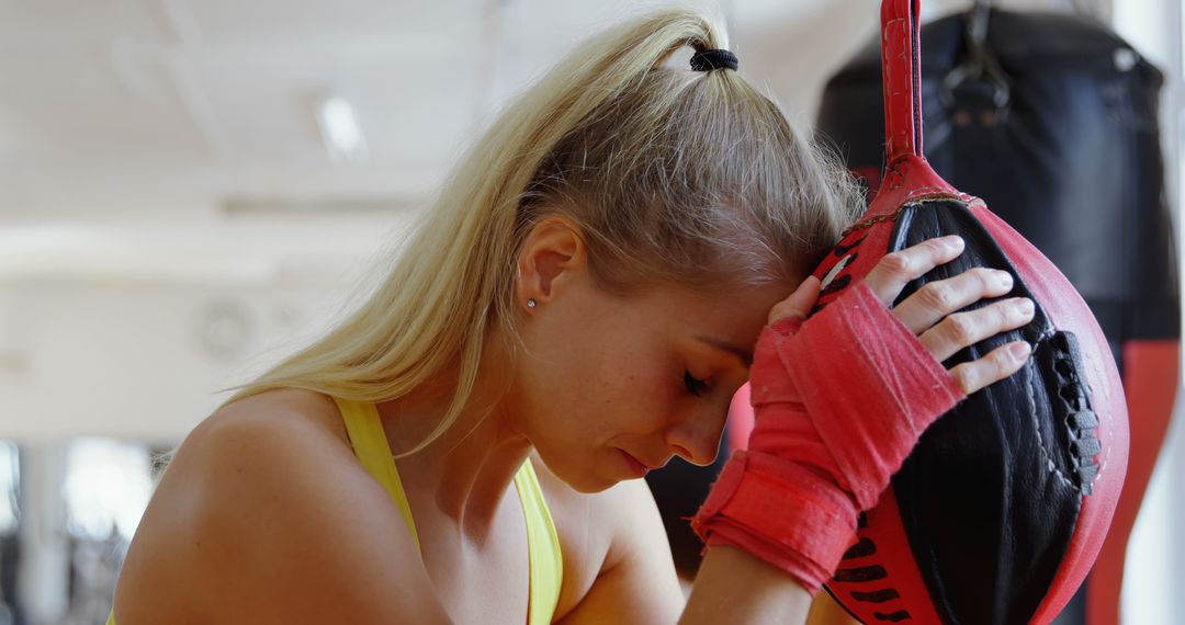 Exhausted Female Boxer Resting Her Head on Boxing Bag - Free Images, Stock Photos and Pictures on Pikwizard.com