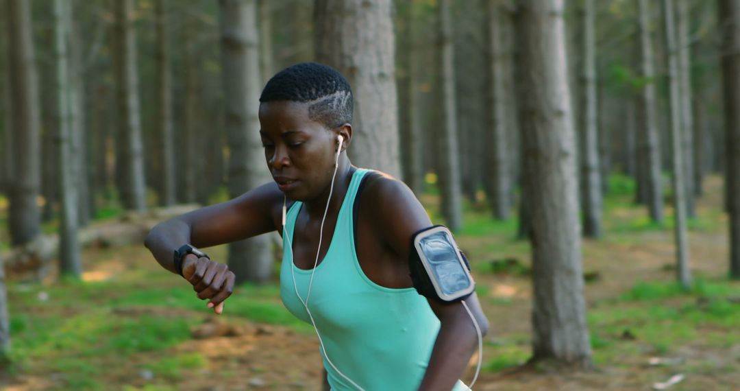 Focused woman runner checking smartwatch in forest - Free Images, Stock Photos and Pictures on Pikwizard.com