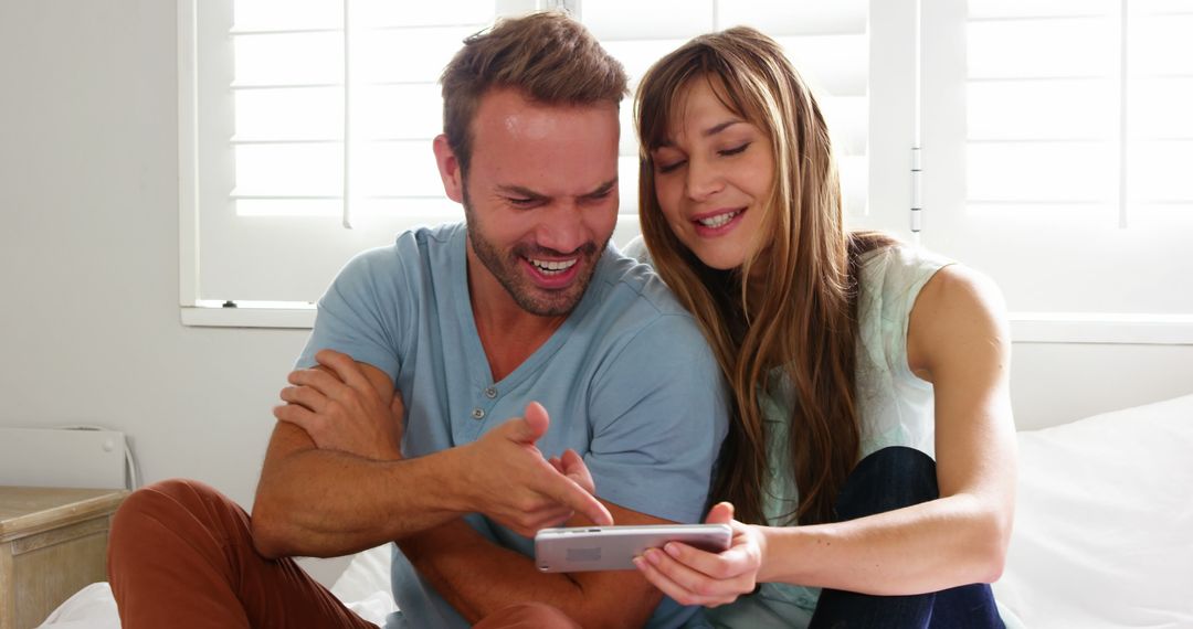 Joyful Caucasian Couple Smiling at Smartphone Together