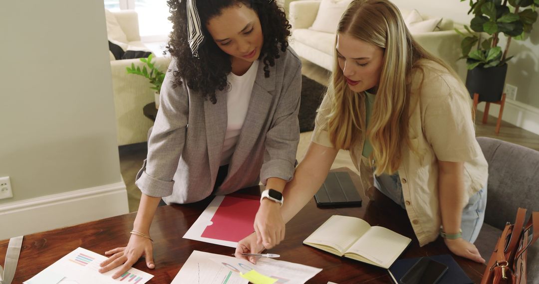 Diverse Female Colleagues Analyzing Charts in Modern Workspace