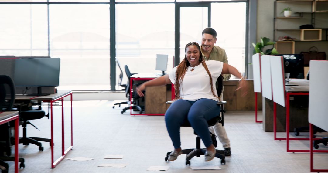 Colleagues Engaging in Playful Office Chair Ride