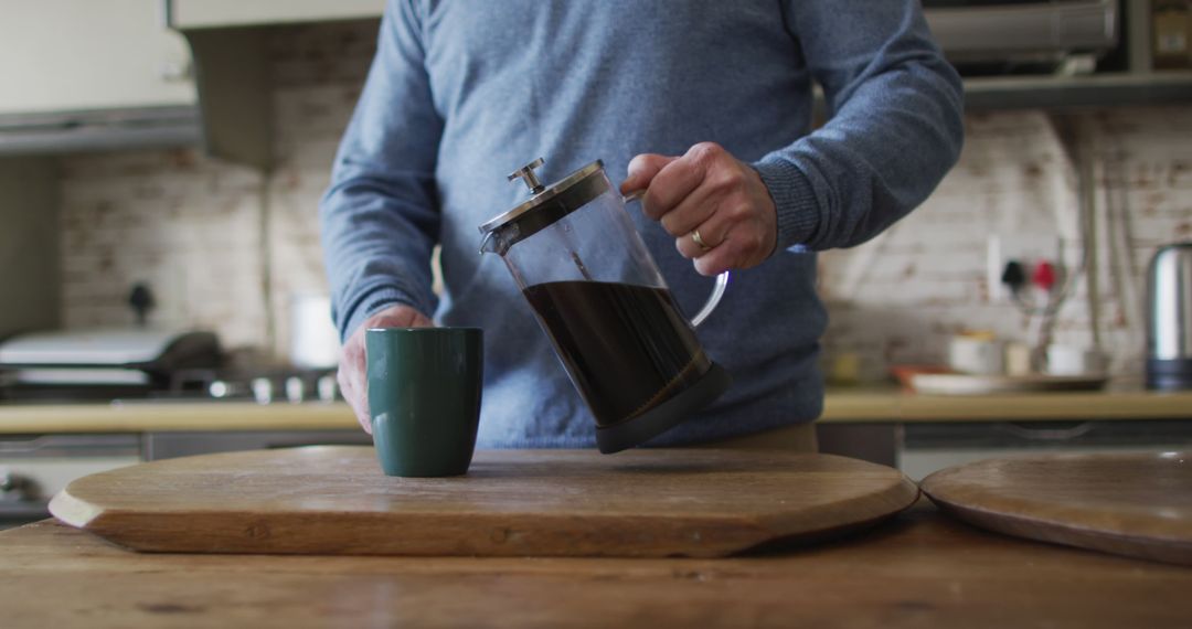 Person Pouring Fresh Black Coffee from French Press into Mug in Cozy Kitchen - Free Images, Stock Photos and Pictures on Pikwizard.com