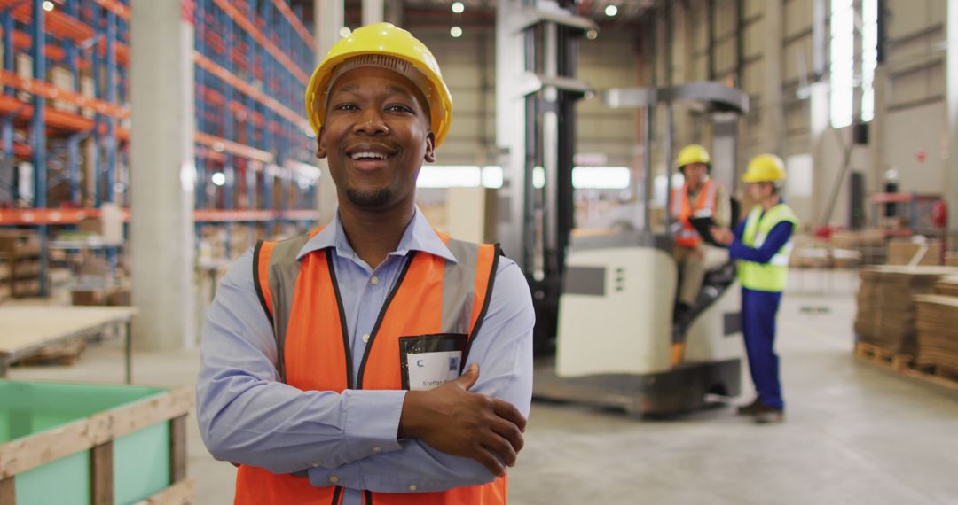 Confident Warehouse Worker Smiling in Warehouse with Colleagues - Free Images, Stock Photos and Pictures on Pikwizard.com