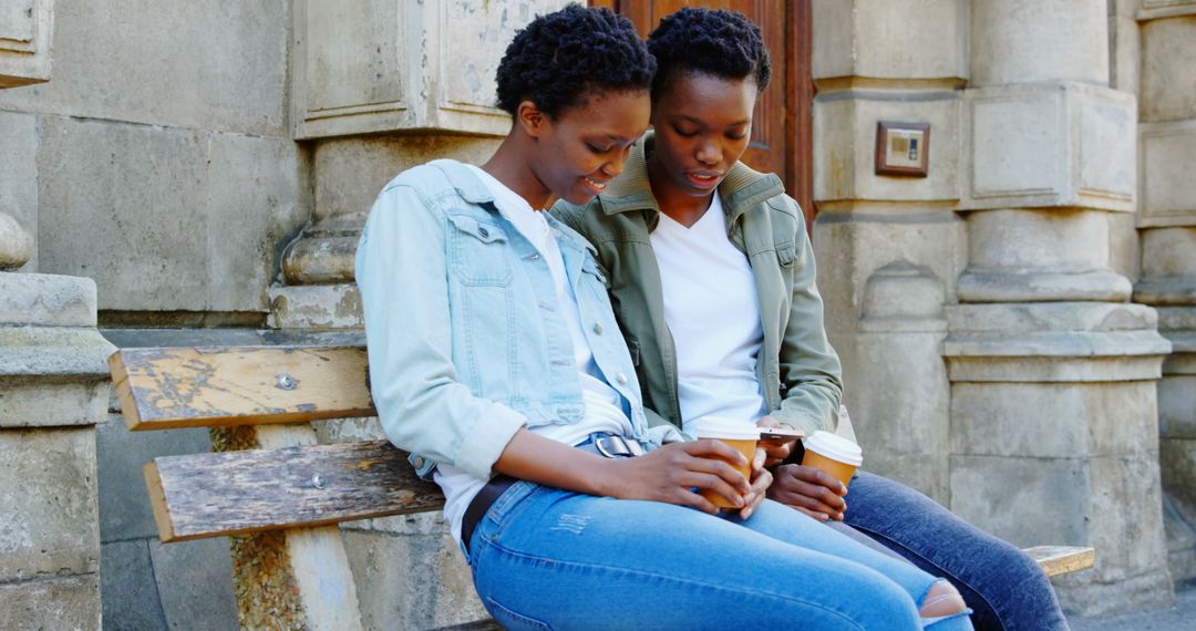 Twin Sisters Enjoy Coffee and Smartphone in Urban Setting
