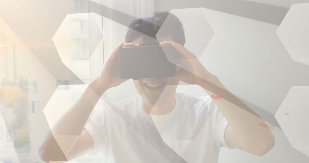 Asian Man Engaged in Virtual Reality Experience Near Sunlit Window