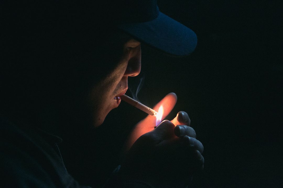 Man in Black Cap Lighting Cigarette during Nighttime - Free Images, Stock Photos and Pictures on Pikwizard.com