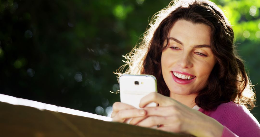 Smiling Woman Using Smartphone in Outdoor Park - Free Images, Stock Photos and Pictures on Pikwizard.com