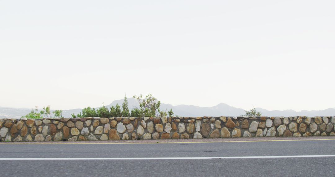 Empty Road with Stone Wall and Scenic Mountain Background - Free Images, Stock Photos and Pictures on Pikwizard.com