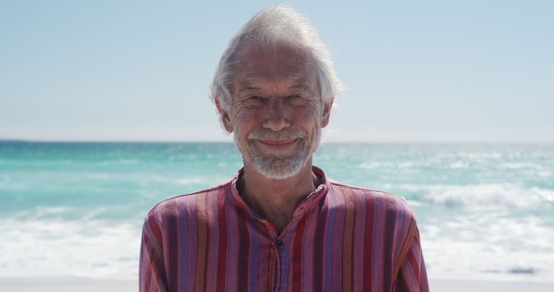 Senior Man Smiling on Sunny Beach with Ocean Background - Free Images, Stock Photos and Pictures on Pikwizard.com