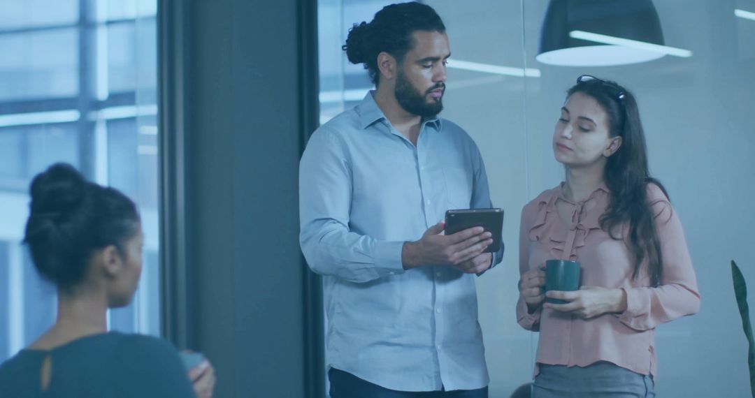 Diverse Colleagues Collaborating Over Tablet in Modern Office
