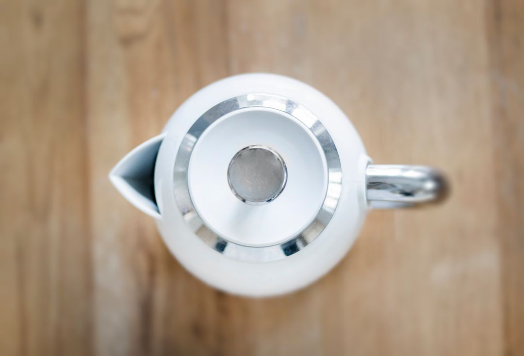 Top View of Modern White Tea Kettle on Wooden Surface
