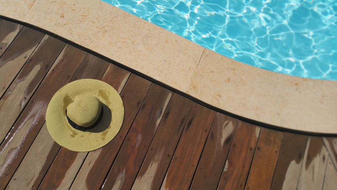 Straw Hat Lying on Wooden Deck by Pool on Sunny Day - Free Images, Stock Photos and Pictures on Pikwizard.com