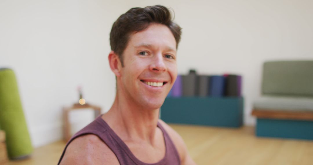 Smiling Man in Lotus Position in Modern Yoga Studio