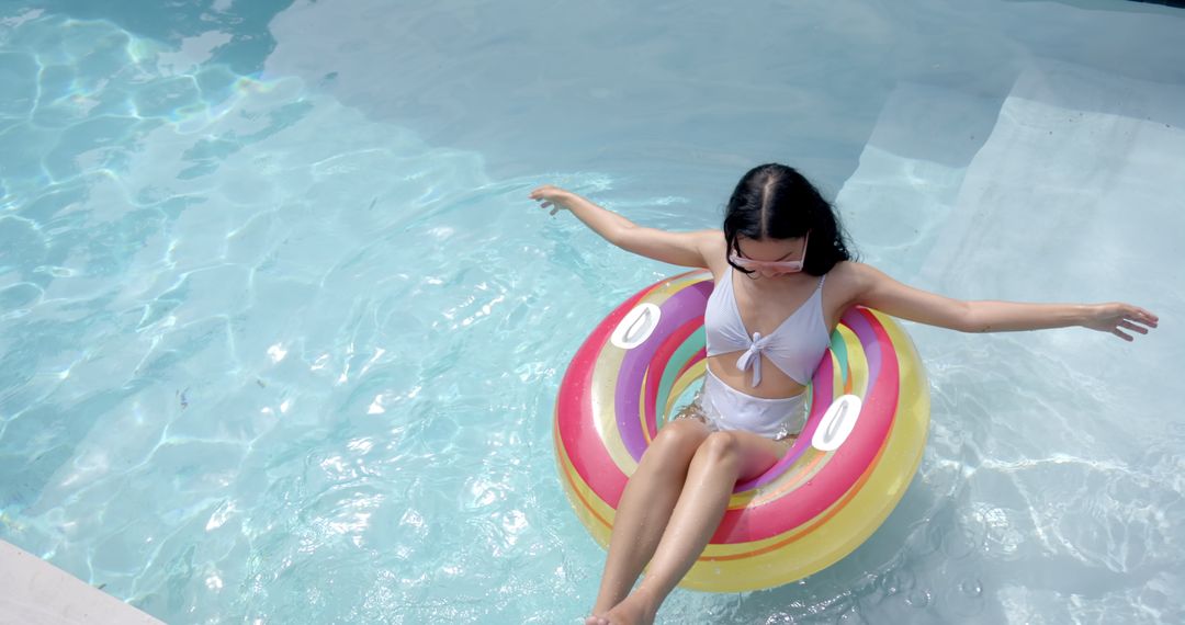 Young Woman Relaxing on Colorful Pool Float in Sunny Weather