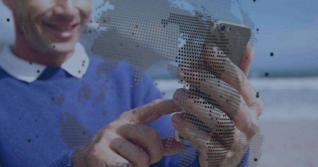 Smiling man tapping smartphone on beach with dotted map overlay and digital connectivity