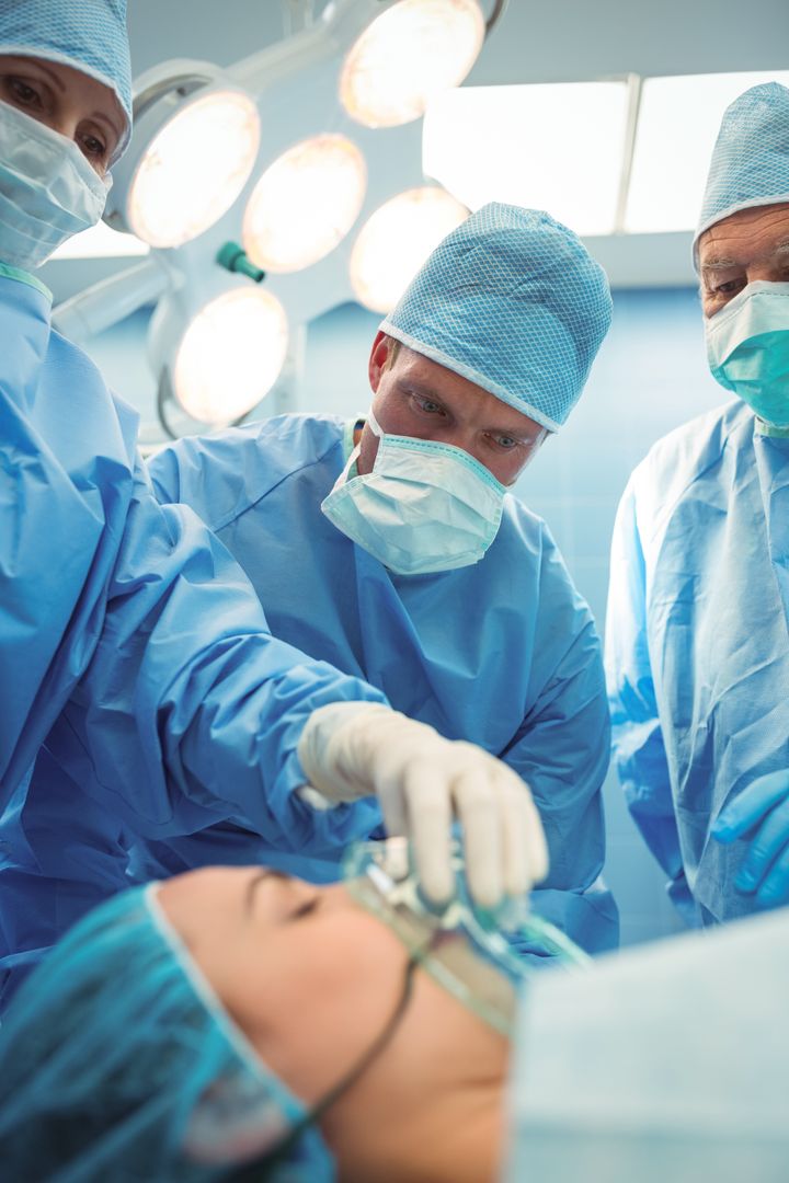 Team of surgeons adjusting oxygen mask on patient mouth in operation theater - Free Images, Stock Photos and Pictures on Pikwizard.com