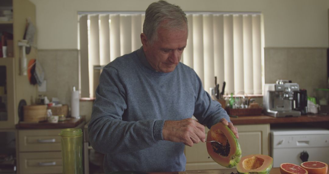 Senior Man Preparing Fresh Papaya in Kitchen - Free Images, Stock Photos and Pictures on Pikwizard.com