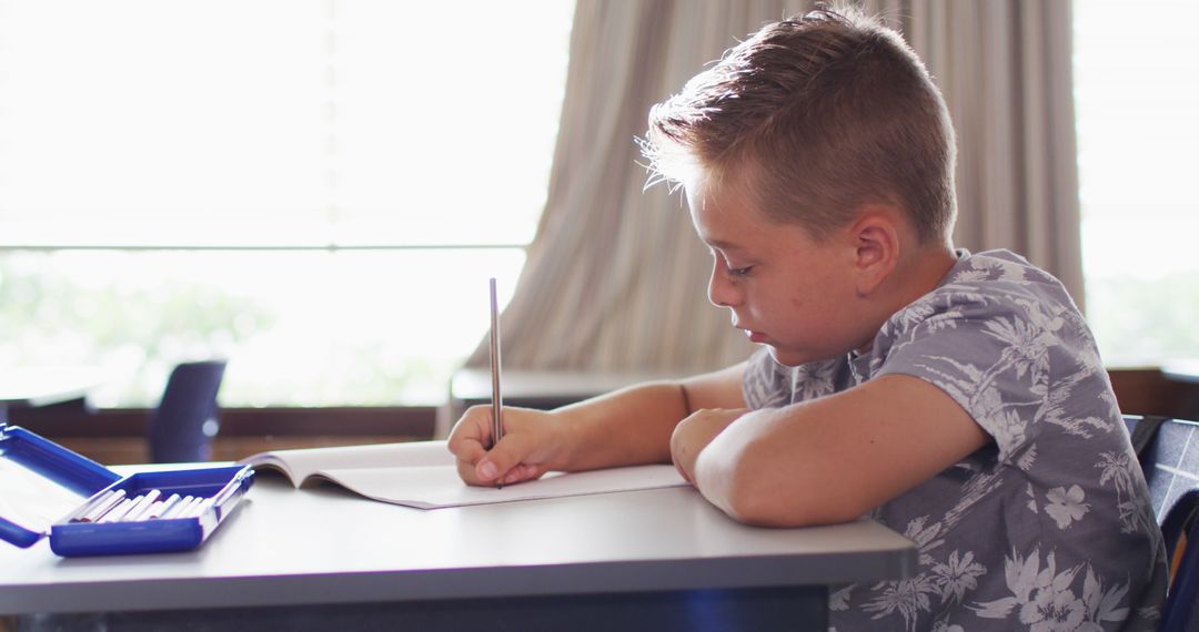 Focused Schoolboy Writing Notes in Classroom Setting