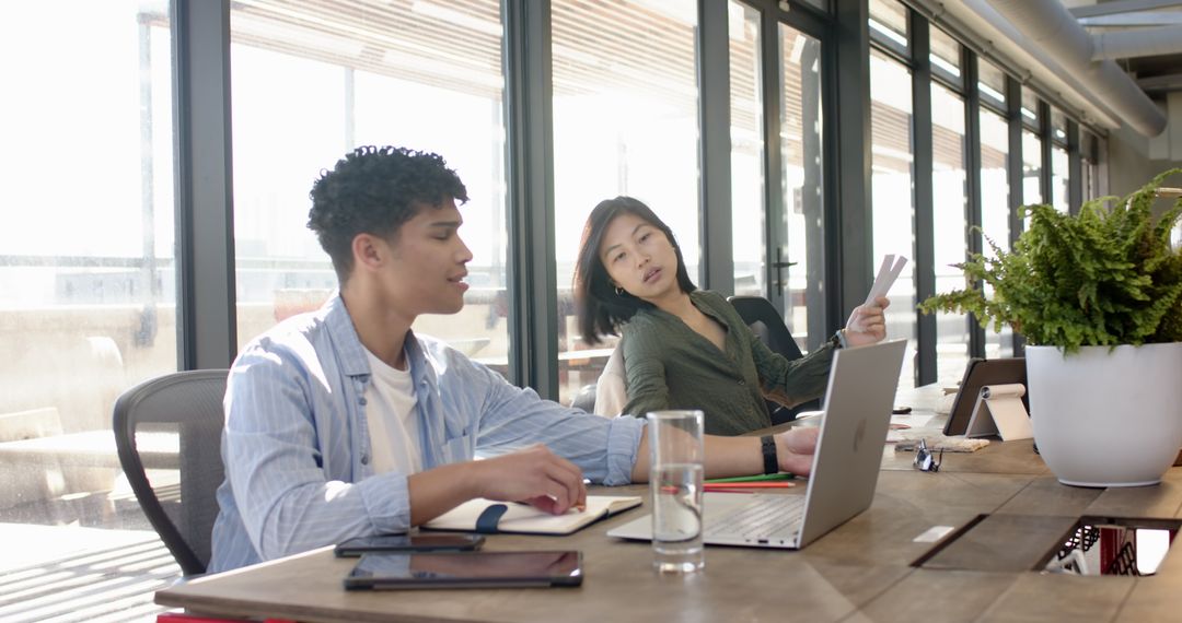Diverse Coworkers Collaborating at Office Desk with Devices