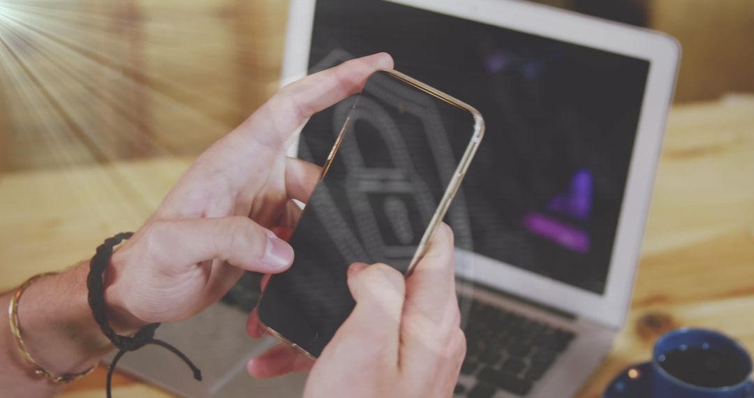 Person Using Smartphone in Cozy Sunlit Room with Open Laptop