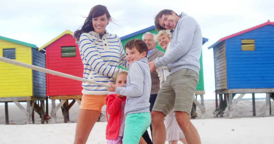 Family Playing Tug of War on Beach with Colorful Beach Huts - Free Images, Stock Photos and Pictures on Pikwizard.com