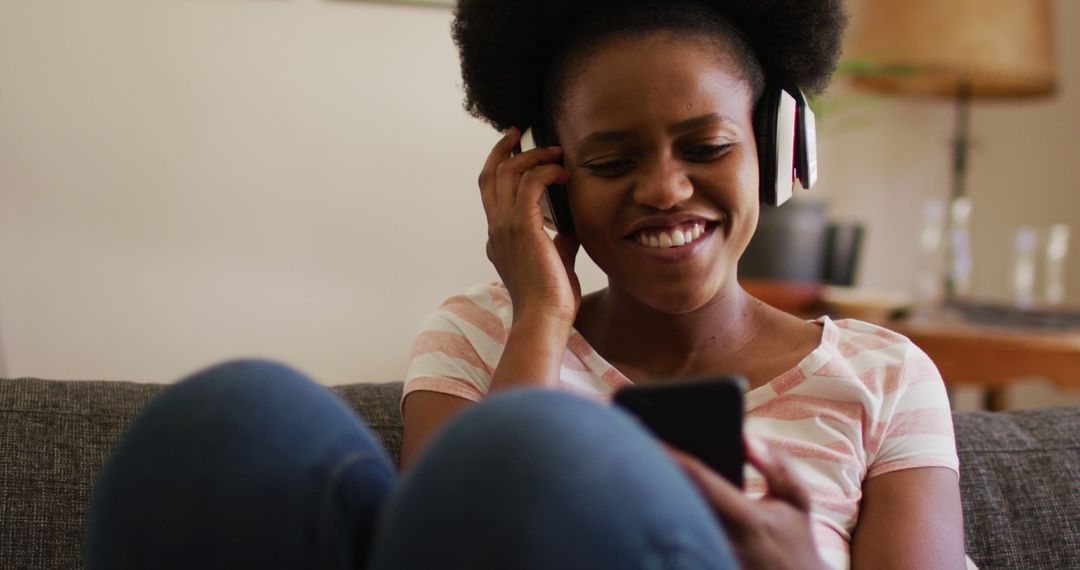 Young African American Woman Enjoying Music on Smartphone at Home - Free Images, Stock Photos and Pictures on Pikwizard.com