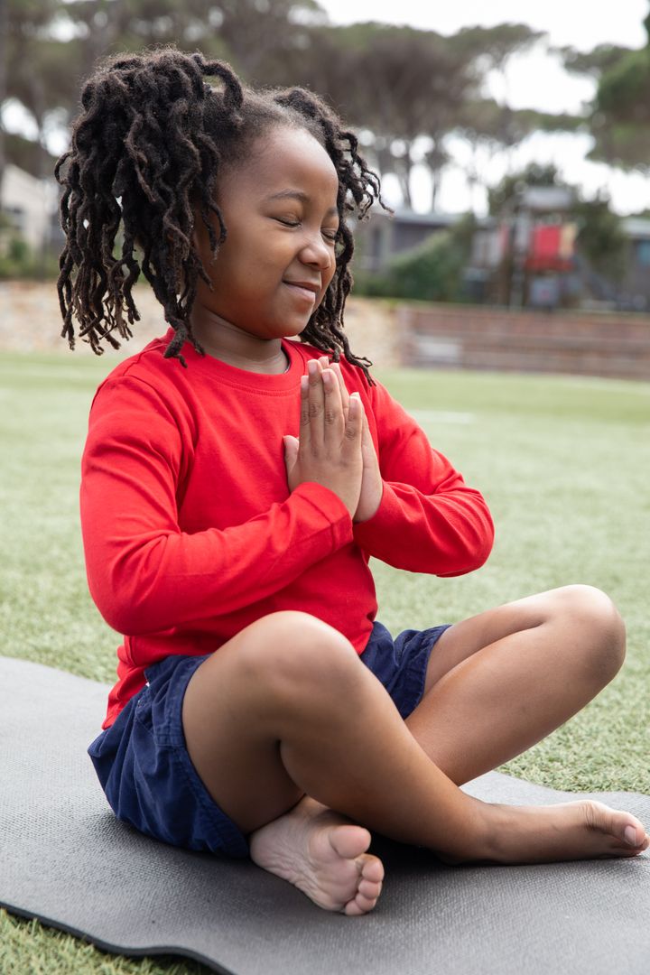 Smiling Child Practicing Mindfulness Outdoors on Yoga Mat