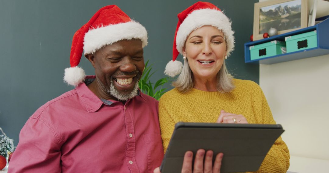 Happy Seniors Wearing Santa Hats Streaming Christmas Greetings - Free Images, Stock Photos and Pictures on Pikwizard.com