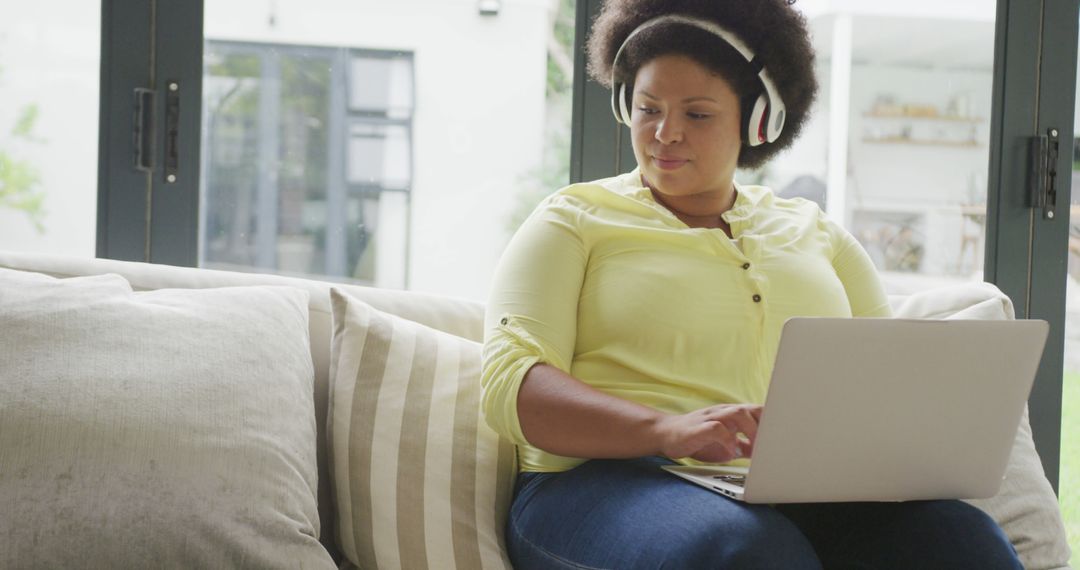 Woman Relaxing on Sofa with Laptop and Headphones - Free Images, Stock Photos and Pictures on Pikwizard.com